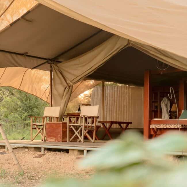 Luxury safari tent with private veranda and director's chairs in the Serengeti bush, Tanzania