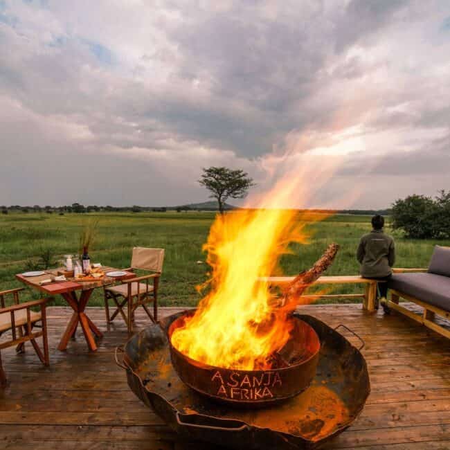 Fireside dining deck overlooking the green Serengeti plains at dusk, Tanzania