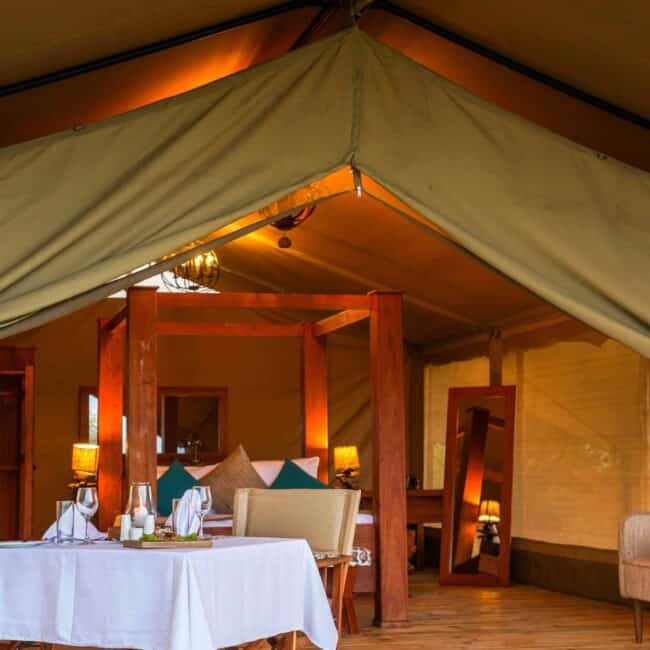Luxury tented suite interior with four-poster bed and private dining table, Serengeti, Tanzania