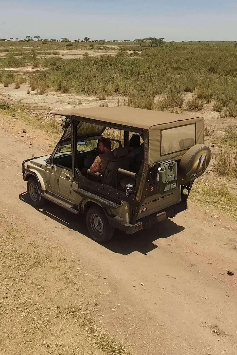 Safari vehicle on a game drive across the open Serengeti plains, Tanzania